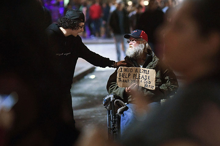 A man takes time to speak with a person in need on Sixth Street in downtown Austin