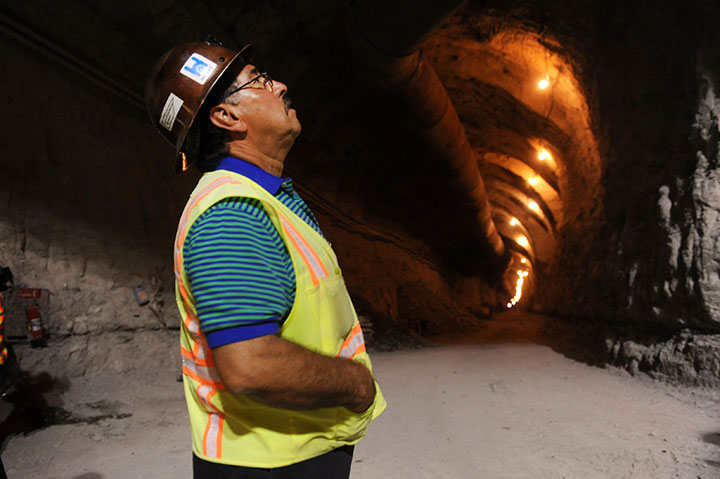 A worker watches as media representatives are lowered into the Waller Creek tunnel construction site