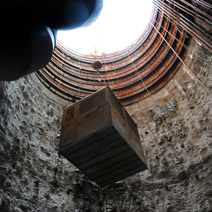 Workers and media representatives are lowered down the access shaft of the Waller Creek tunnel construction site